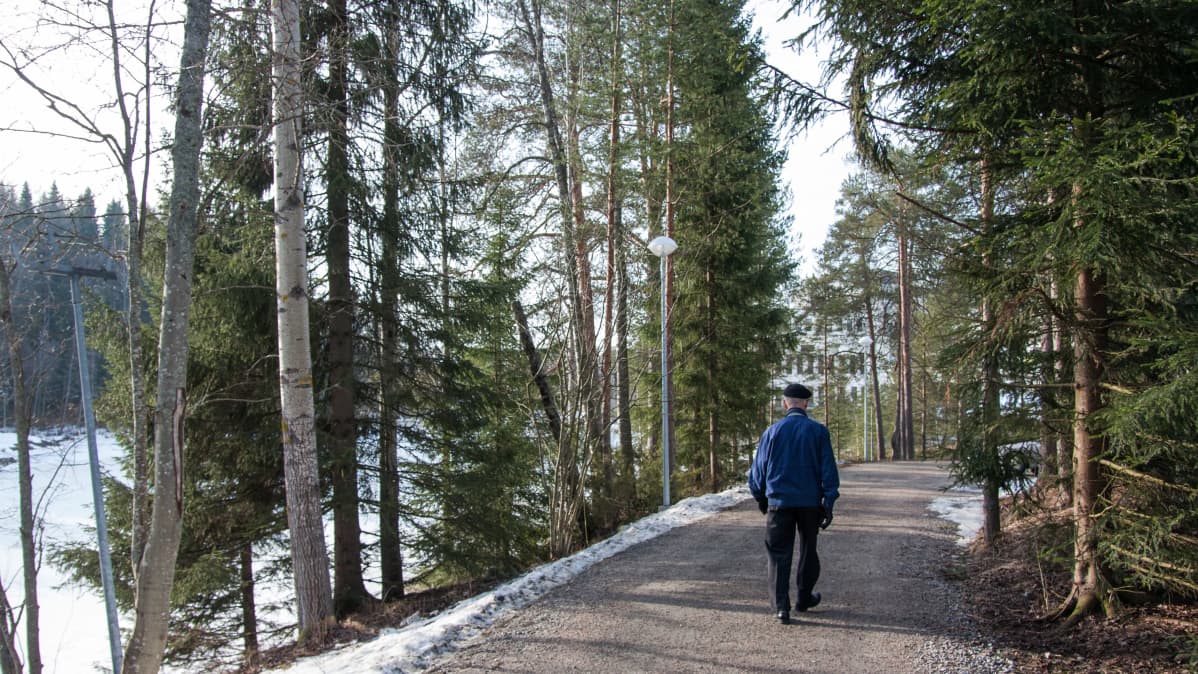 Mies kävelee puistossa.