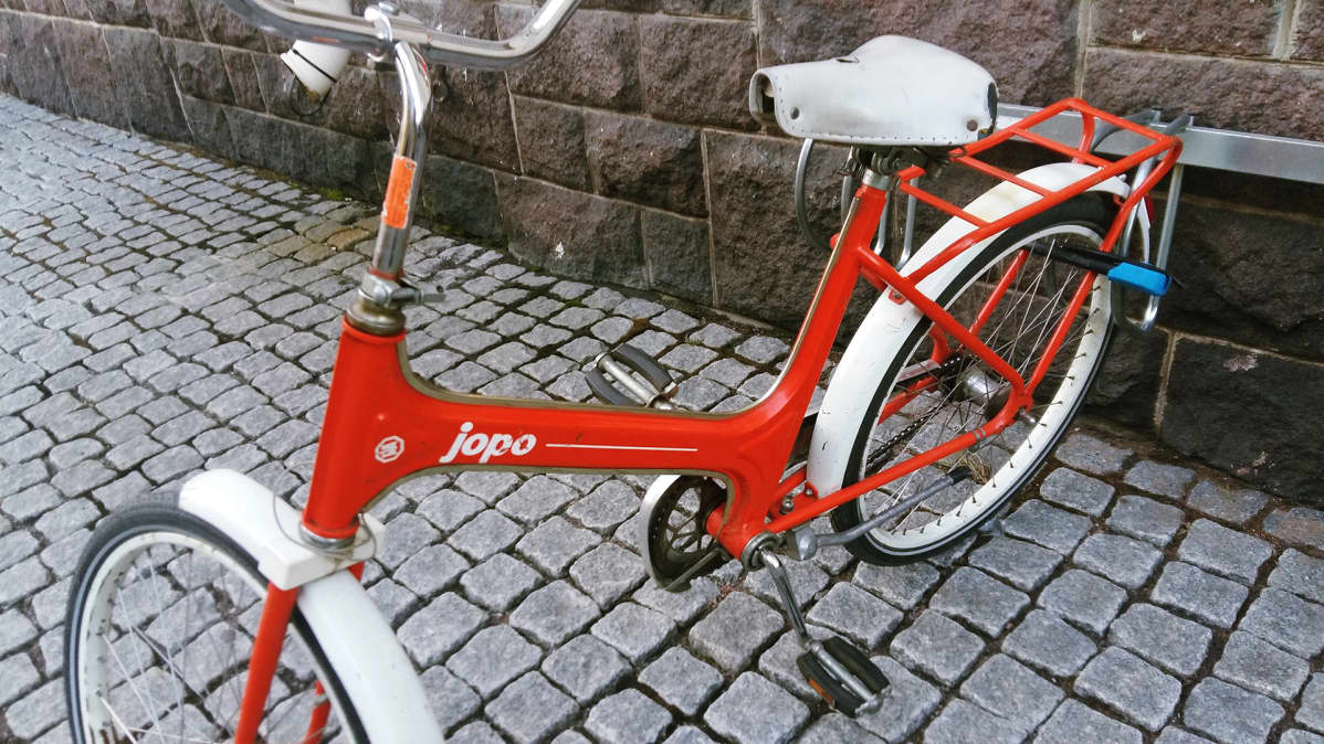 Jopo-pyörä lukittuna takarenkaasta telineeseen.