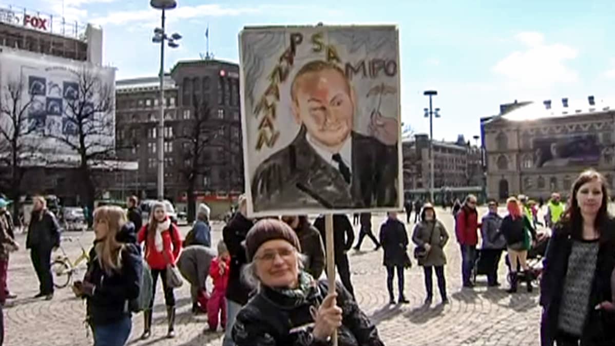 nainen plakaatin kanssa torilla
