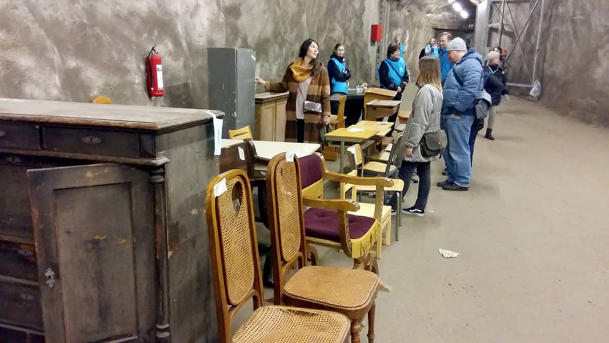 ihmisiä ja huonekaluja väestösuojassa
