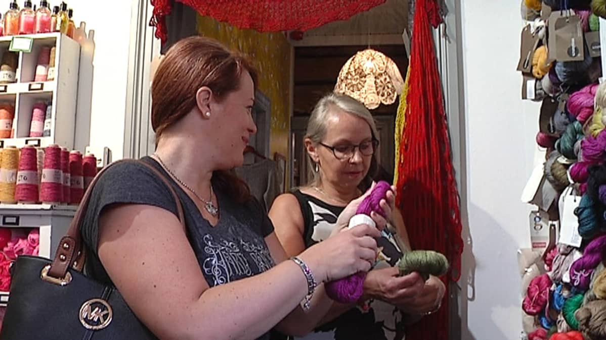 Merja Savolainen ja Raija Kivioja hypistelevät lankoja lankakaupassa.