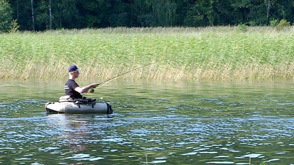 Mies kalastaa perho-ongella kelluntarenkaassa.