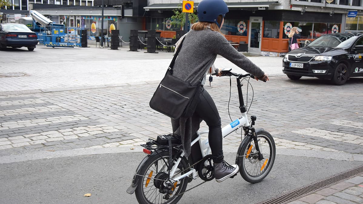 Nainen pyöräilee sähköpolkupyörällä kadulla