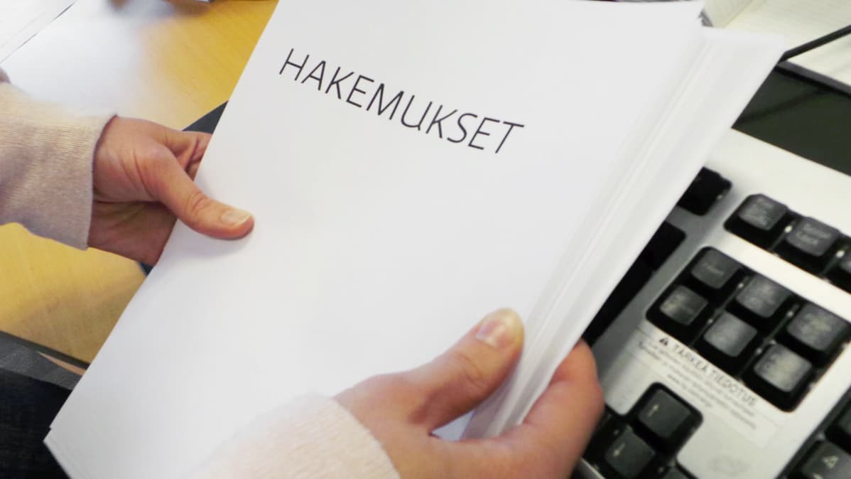 Nainen pitelee hakemuspinoa käsissään.