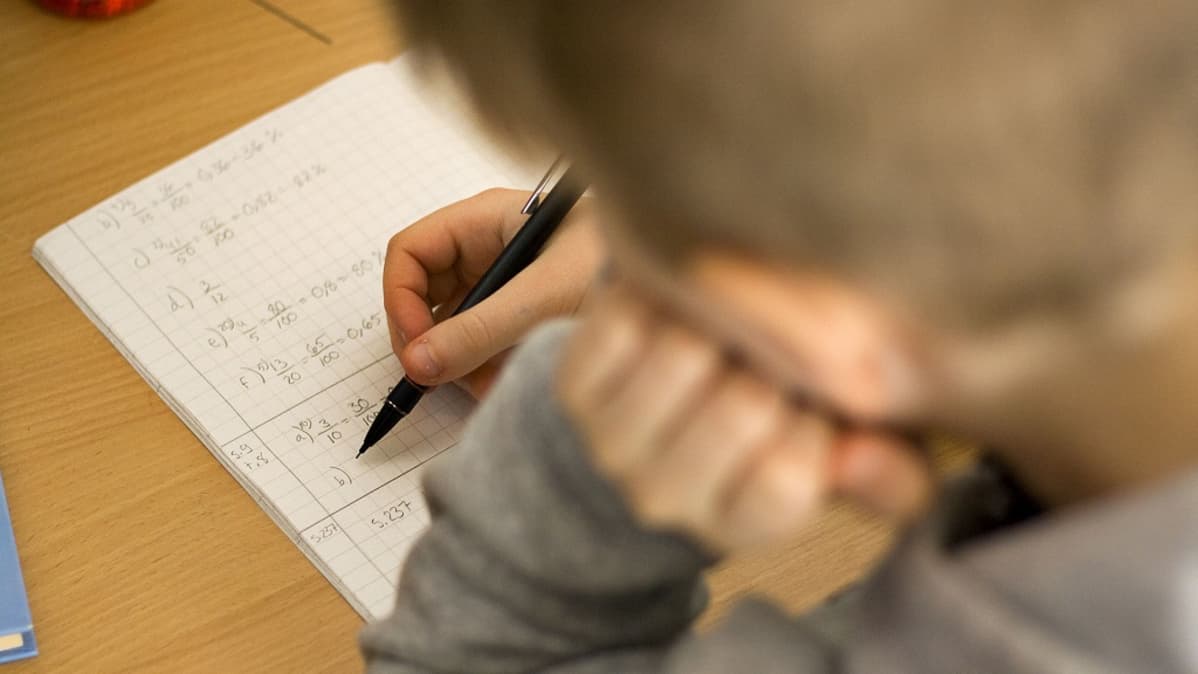 Lapsi laskee matematiikan tehtäviä.