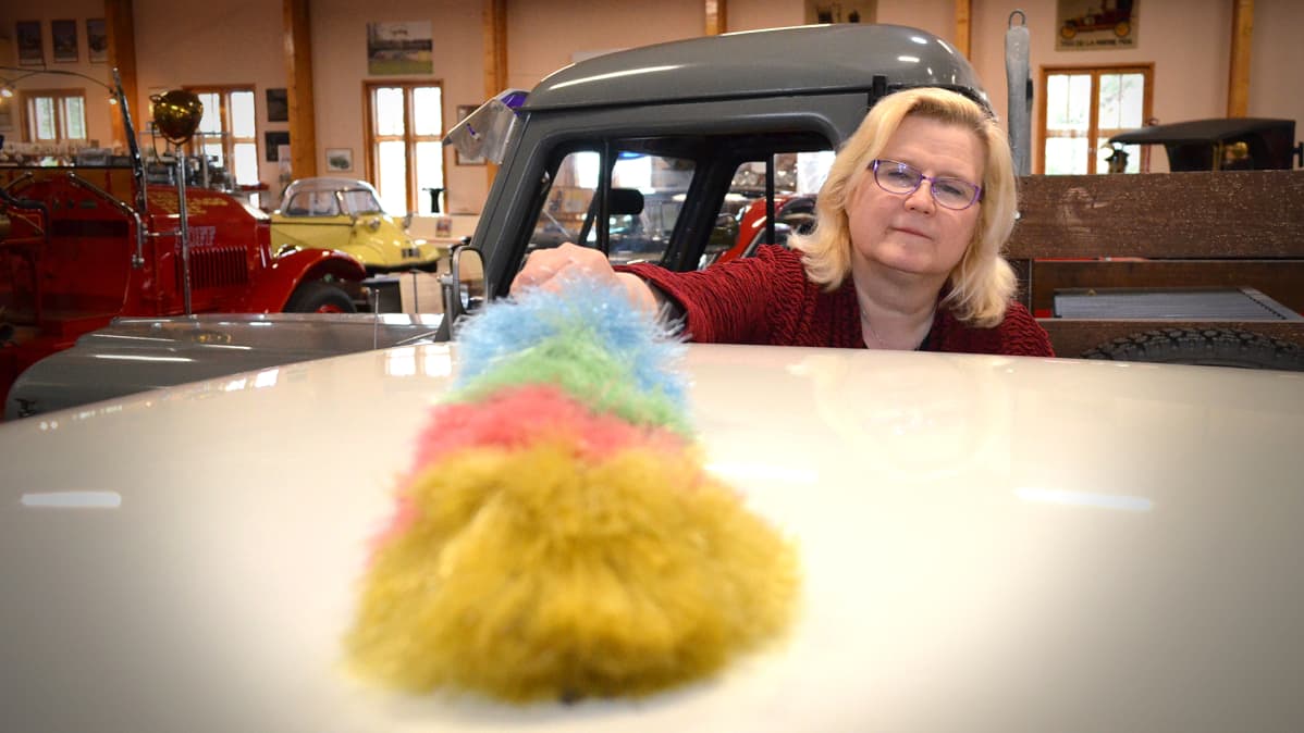 Leila Suutarinen pyyhkii pölyjä vanhan auton katolta.