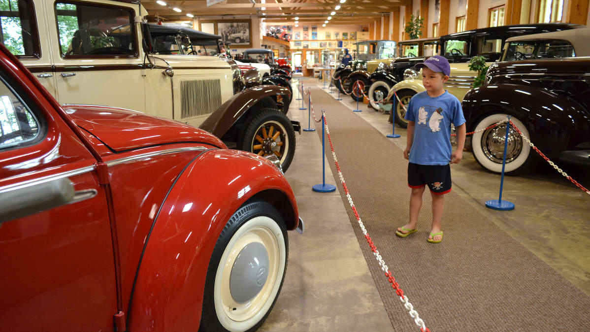 Poika katselee museoautoja Vehoniemen automuseossa.