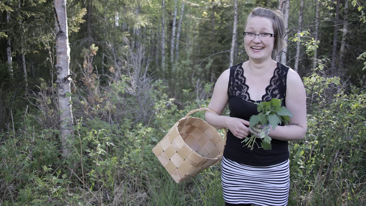 nainen seisoo metsässä korin kanssa