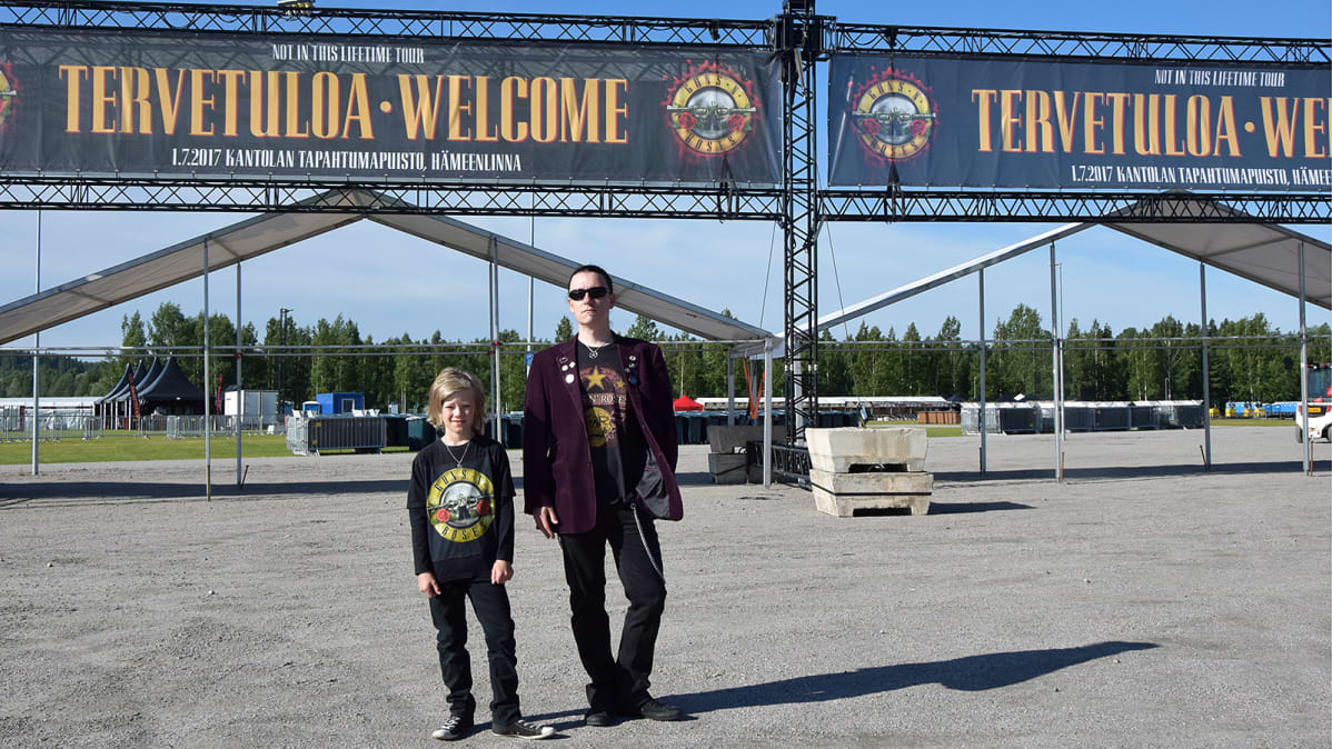 Isä ja poika Guns N' Rosesin keikkapaikan pääportin edessä