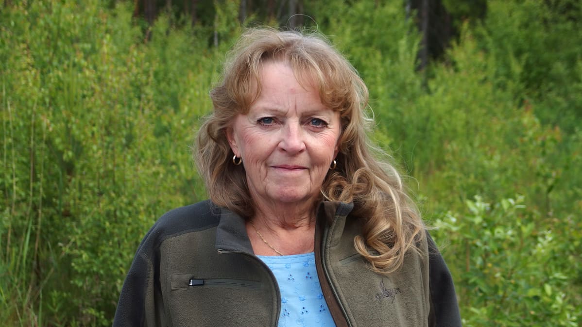 Nainen katsoo kameraan.