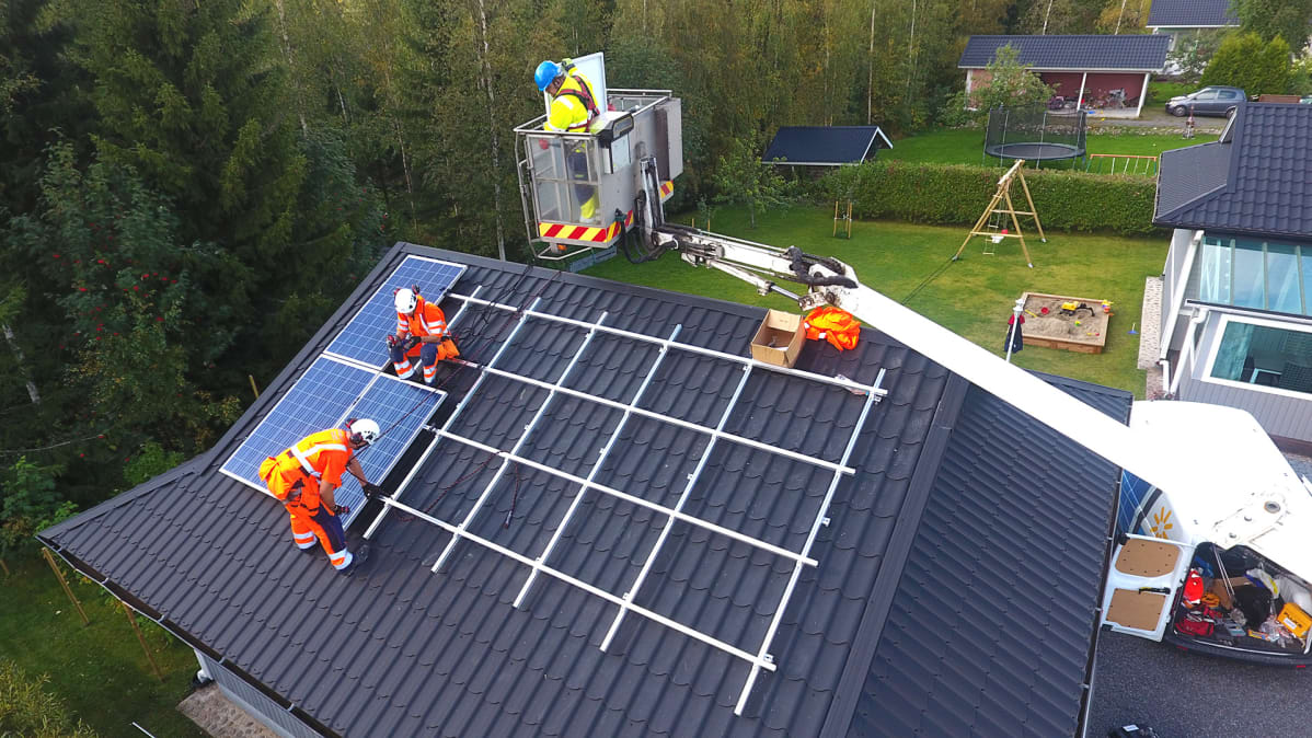 Miehiä asentamassa aurinkopaneeleja katolle.