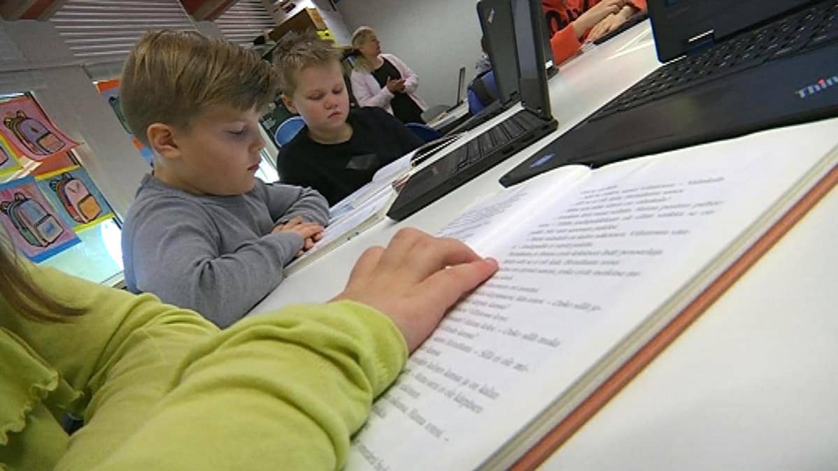 koululaiset lukevat luokassa kirjaa