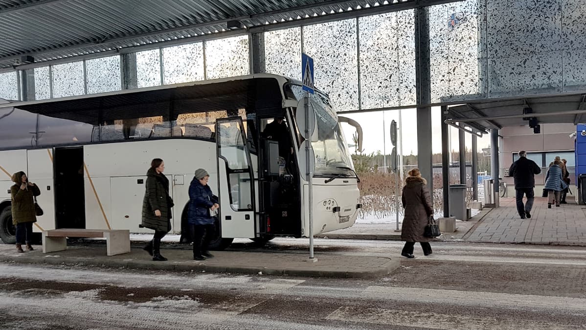 Venäläinen turistibussi Nuijamaan rajatarkastusasemalla menossa Lappeenrantaan. Matkustajat kävelevät kohti passintarkastusta.