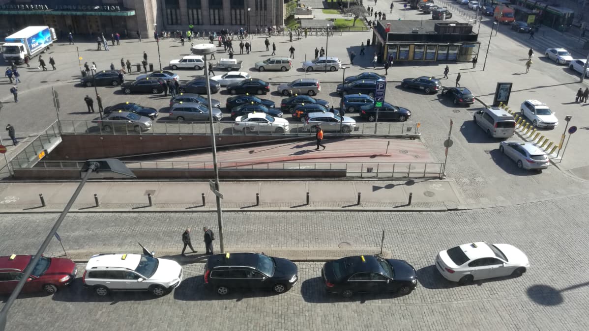 Bild tagen uppifrån på taxiområdet intill järnvägsstationen i Helsingfors. Flera taxibilar har samlats för en demonstration