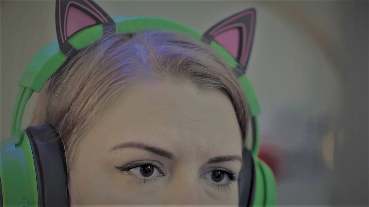 Kati pelaa videopeliä kuulokkeet päässään.