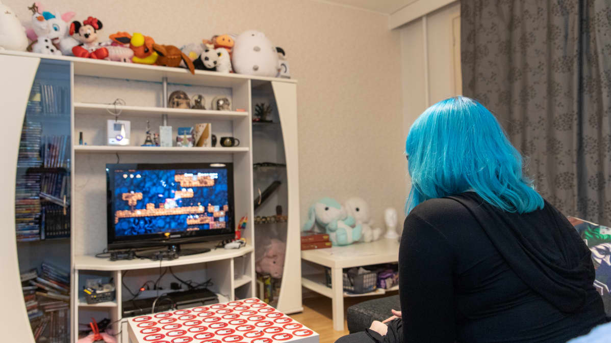 hlö pelaa play station peliä olohuoneessa kotonaan