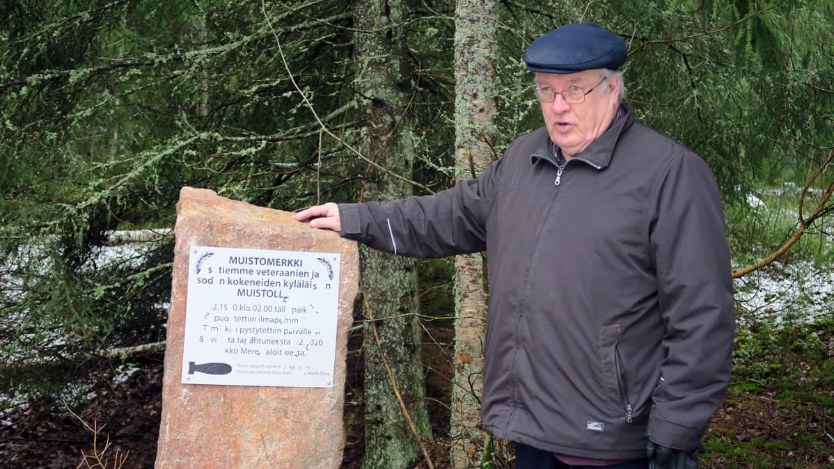 Martti Pura seisomassa muistomerkin vierellä