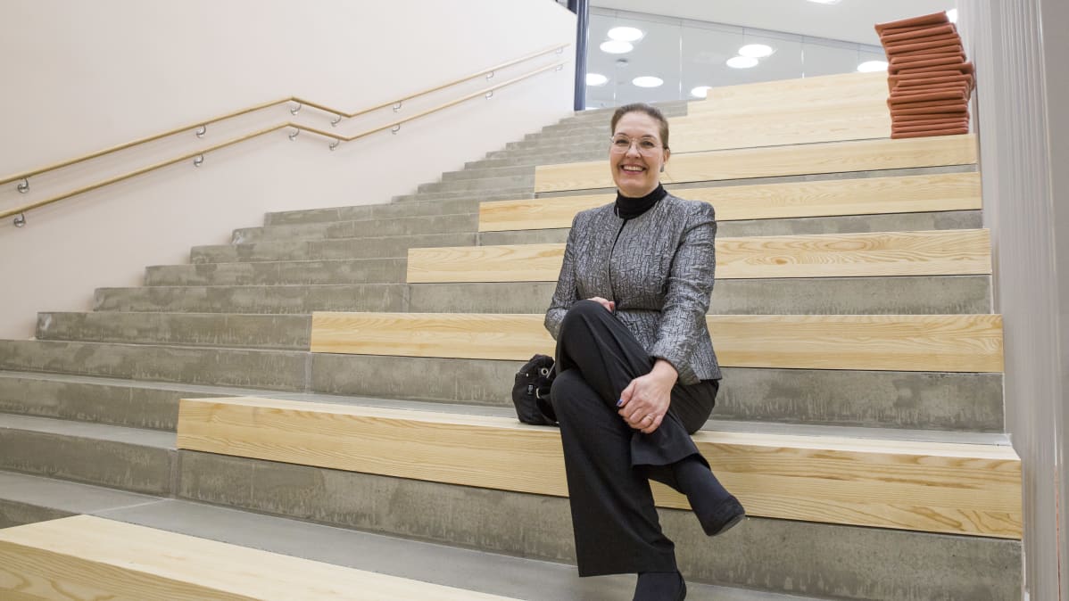 Porvoon kaupungin vt. sivistysjohtaja Sari Gustafsson istuu uuden, ruotsinkielisen Strömborgska skolanin rappusilla.