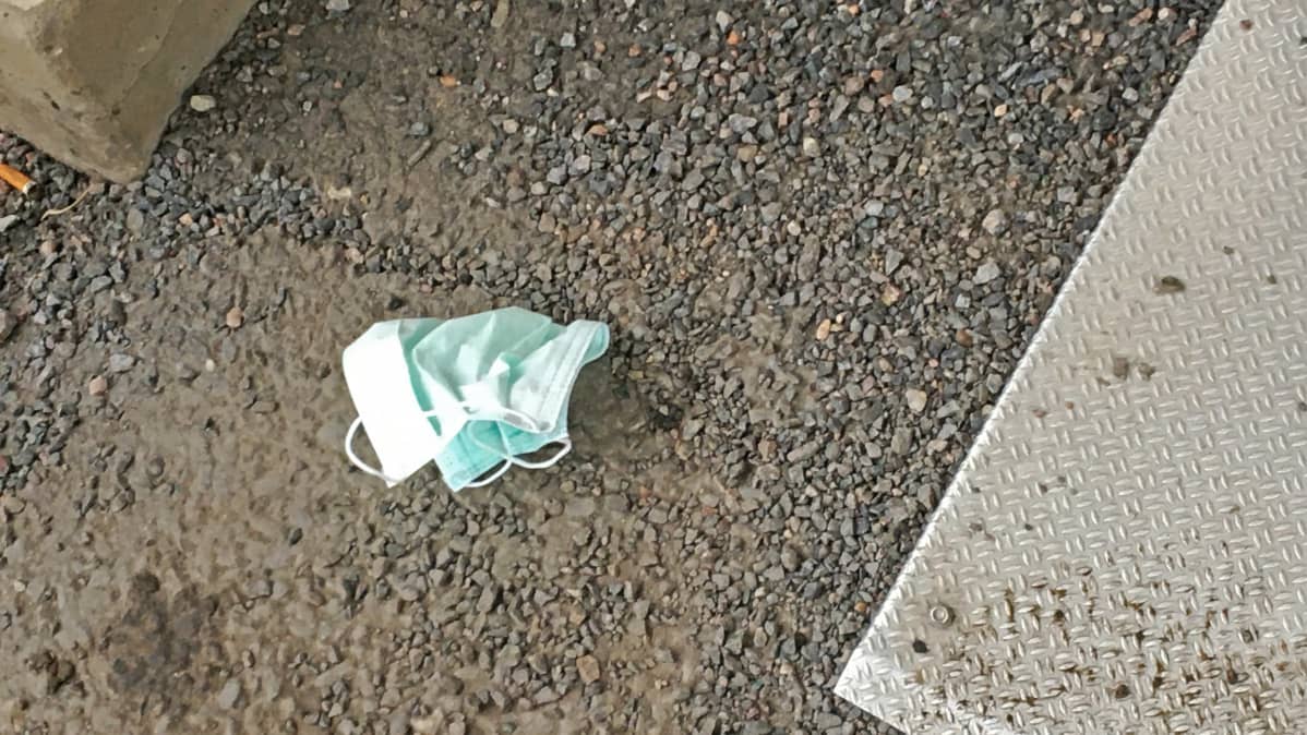 Käytetty hengityssuojain heitettynä maahan.