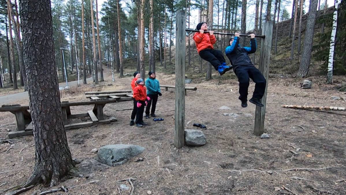 Isä ja poika vetävät ulkona leukoja.