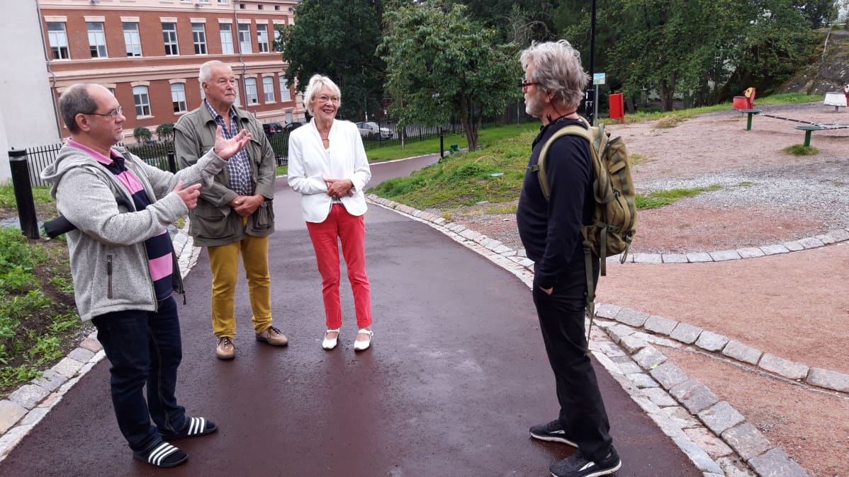Puolalanpuiston puiden luona joukko kaupunkilaisia.