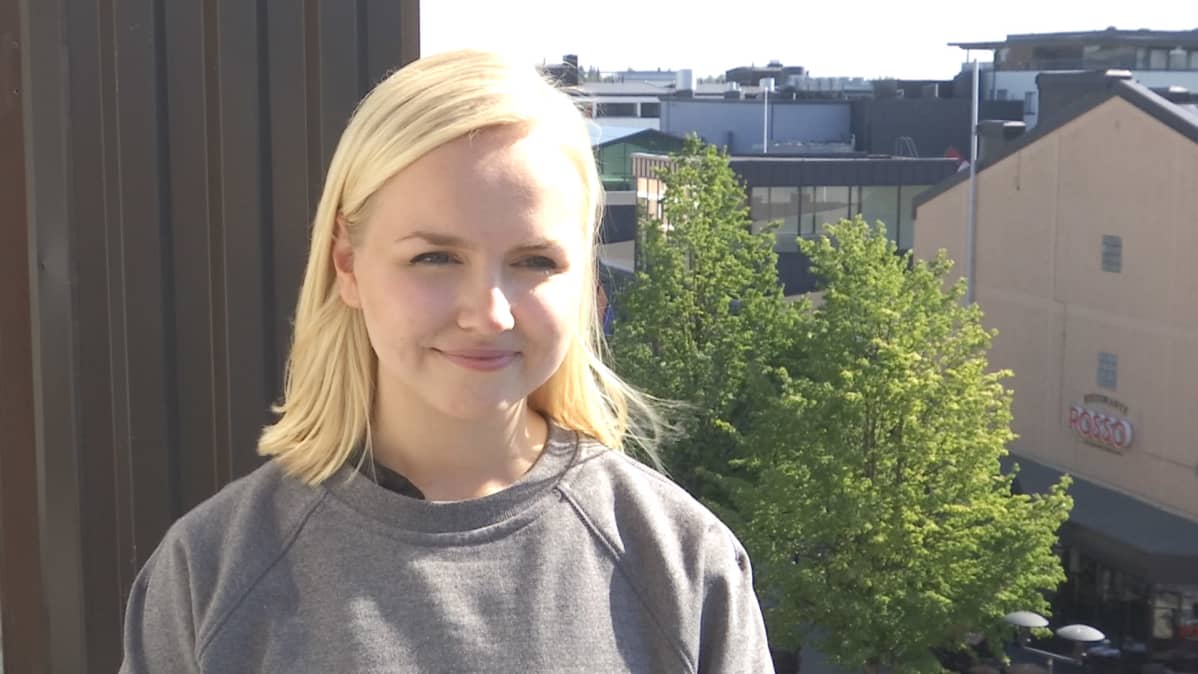 Miisa Pihlaja hymyilee parvekkeella. Taustalla Kokkolan kattoja.
