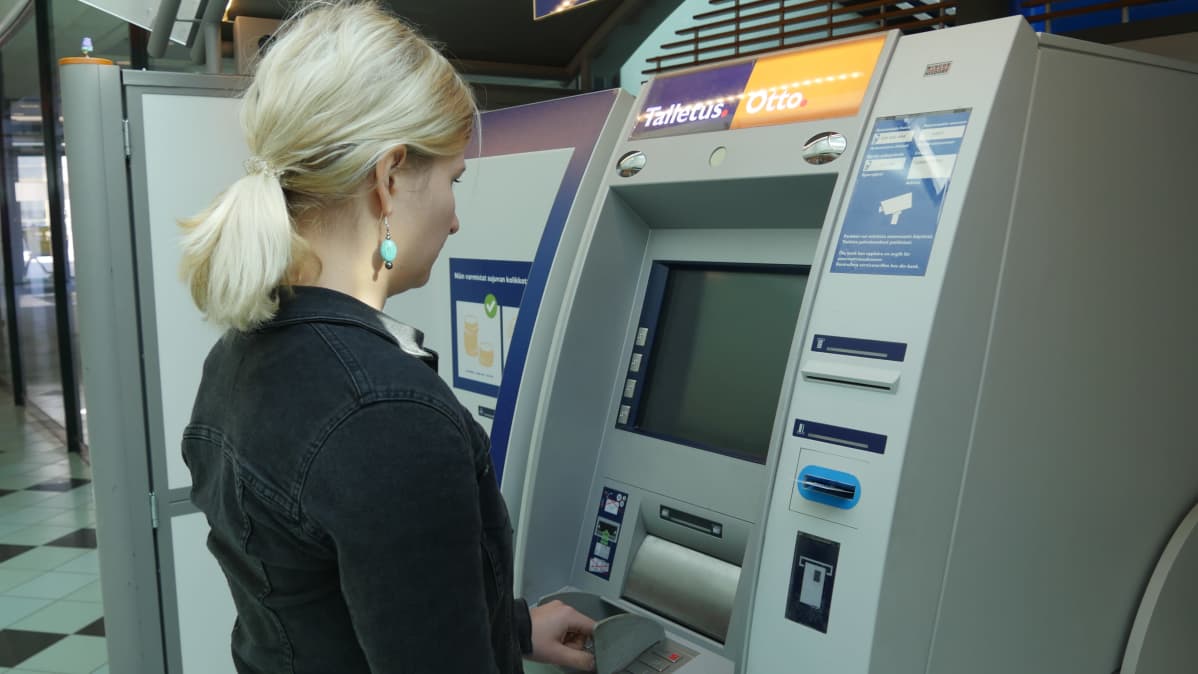 Nainen pankkiautomaatilla nostamassa rahaa.