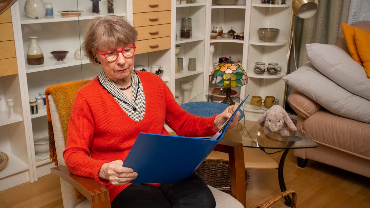 Sirkka-Liisa Kivelä katselee valokuvia kansiosta.