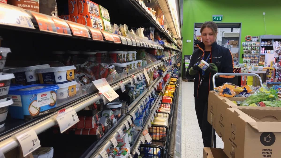 Kaupan työntekijä keräilee ruokatarvikkeita pahvilaatikoihin