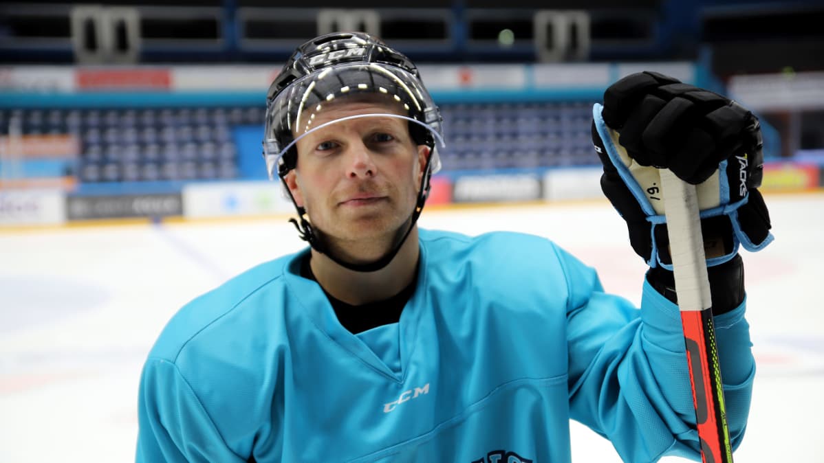 Ryan Lasch maila kädessä, katsoo kameraan.