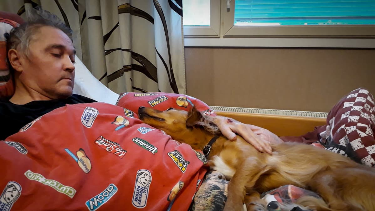 Tumppi Partanen koiransa kanssa kotona sängyssä