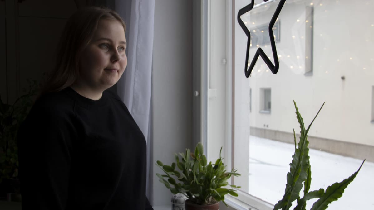 Veronica Helanen kotonaan katsomassa ikkunasta ulos