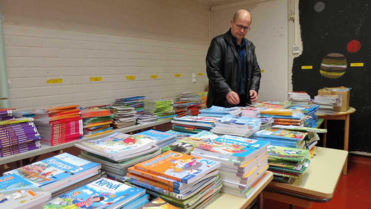 Peltosaaren koulun rehtori Pasi Jalonen katselee poistoon meneviä oppikirjoja