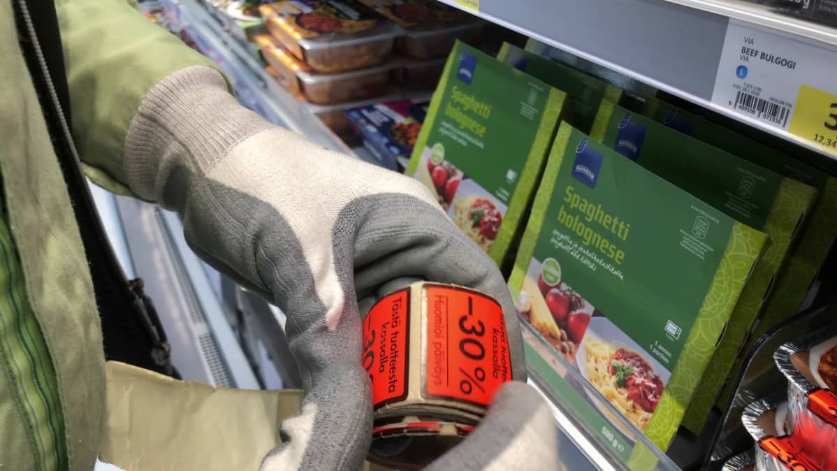 Myyjä kiinnittää isoa alennustarraa spagettipakettiin