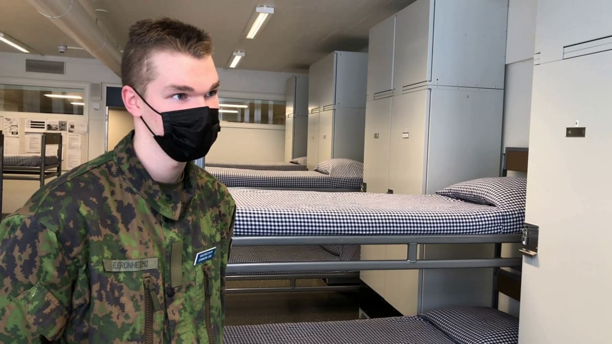 Varusmies sängyn vieressä.