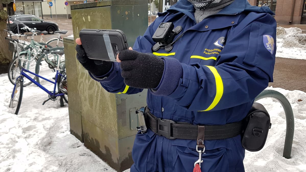 Pysäköinnintarkastaja ottaa valokuvaa autosta
