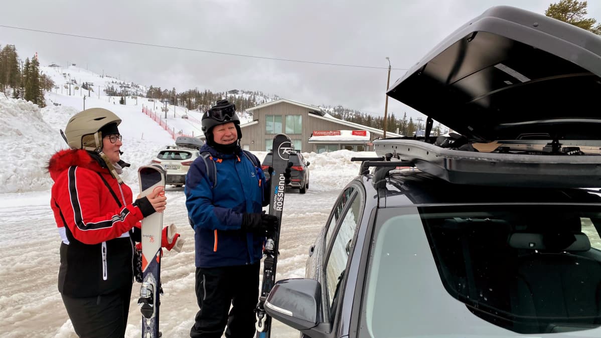 Mies ja nainen laskettelusuksien kanssa Rukan Vuosselin rinteiden parkkipaikalla.
