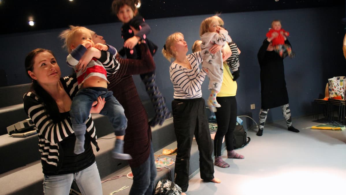 Lapset lentävät lorun tahtiin vanhempien käsivarsilla sanataideryhmässä.