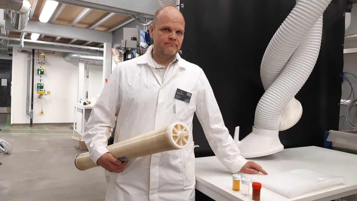 Professori Mika Mänttäri pitää kädessään membraanisuodatinta.