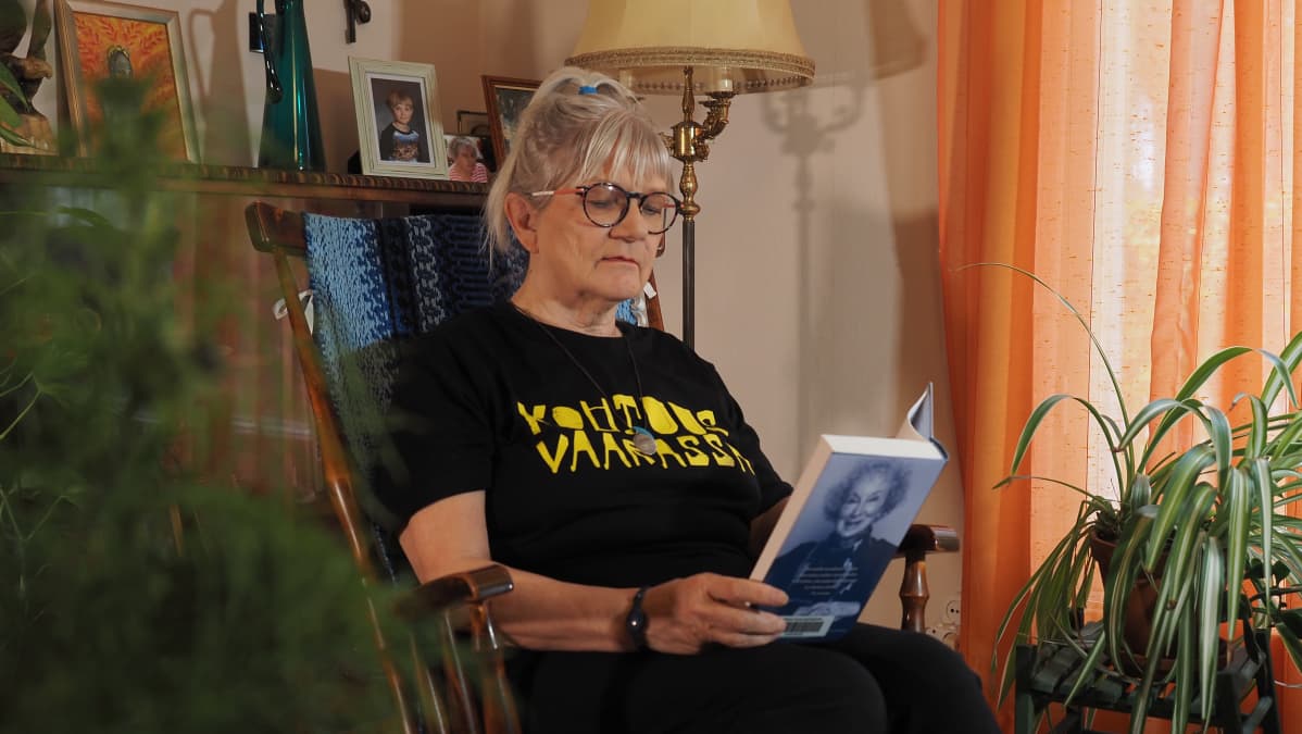 Kirjailija Ulla Vaarnamo lukee kirjaa kiikkutuolissa.