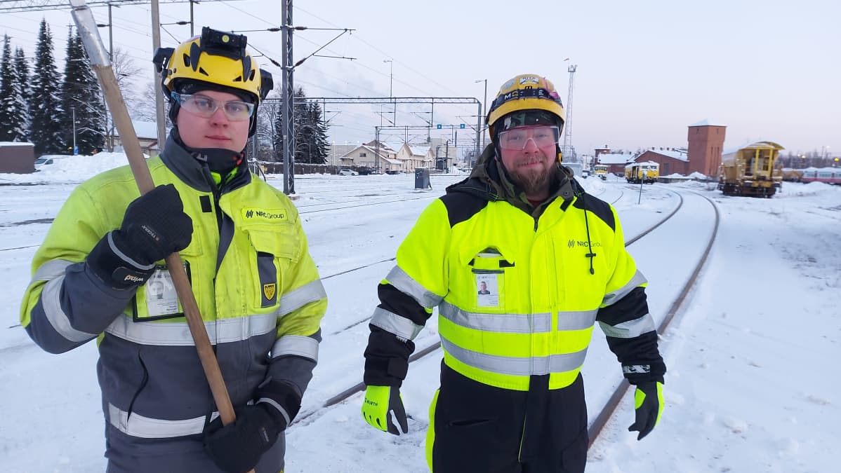 Rata-asentajat työvarusteet päällä Joensuun rautatieaseman junaraiteden edessä pakkassäässä.