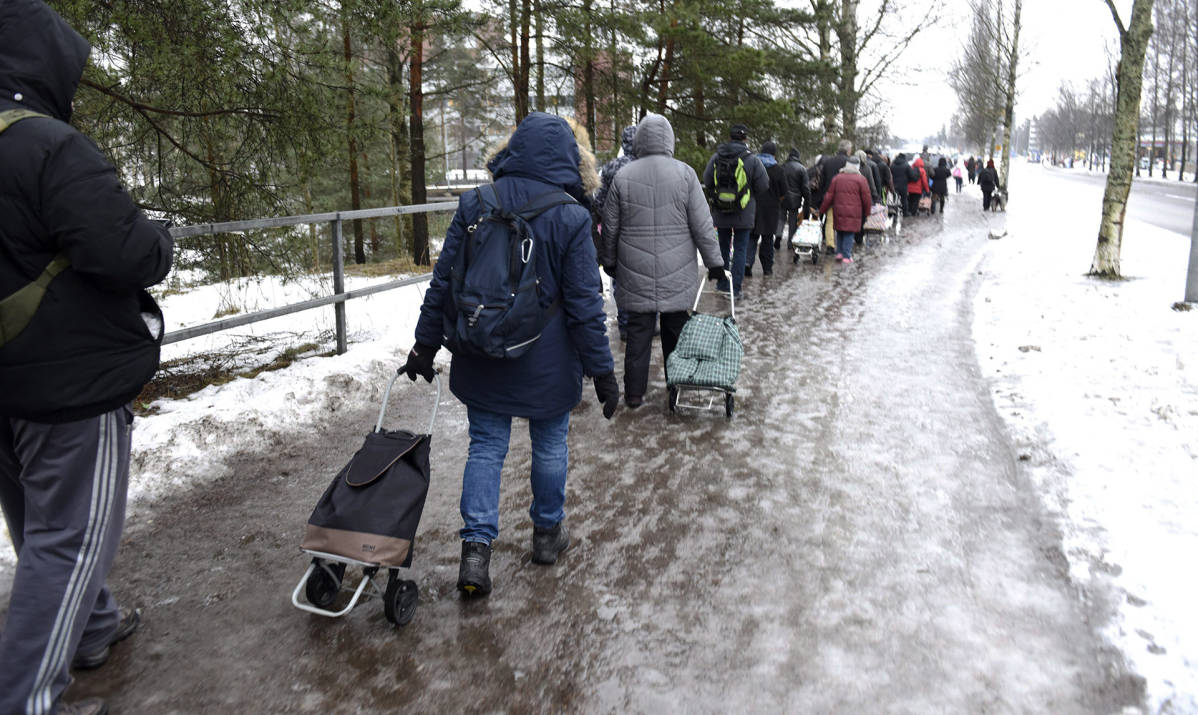 Ihmiset jonottivat elintarvikkeita jäisellä tiellä Helsingin Myllypurossa.