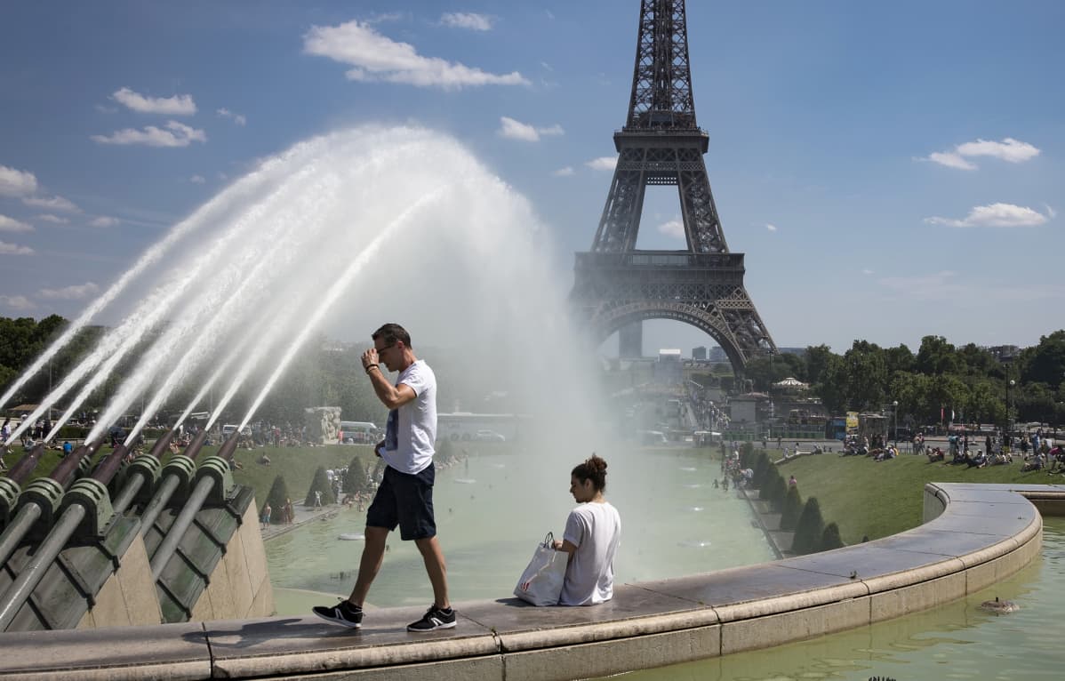 mies kävelee ja nainen istuu Eiffel-tornin edessä.