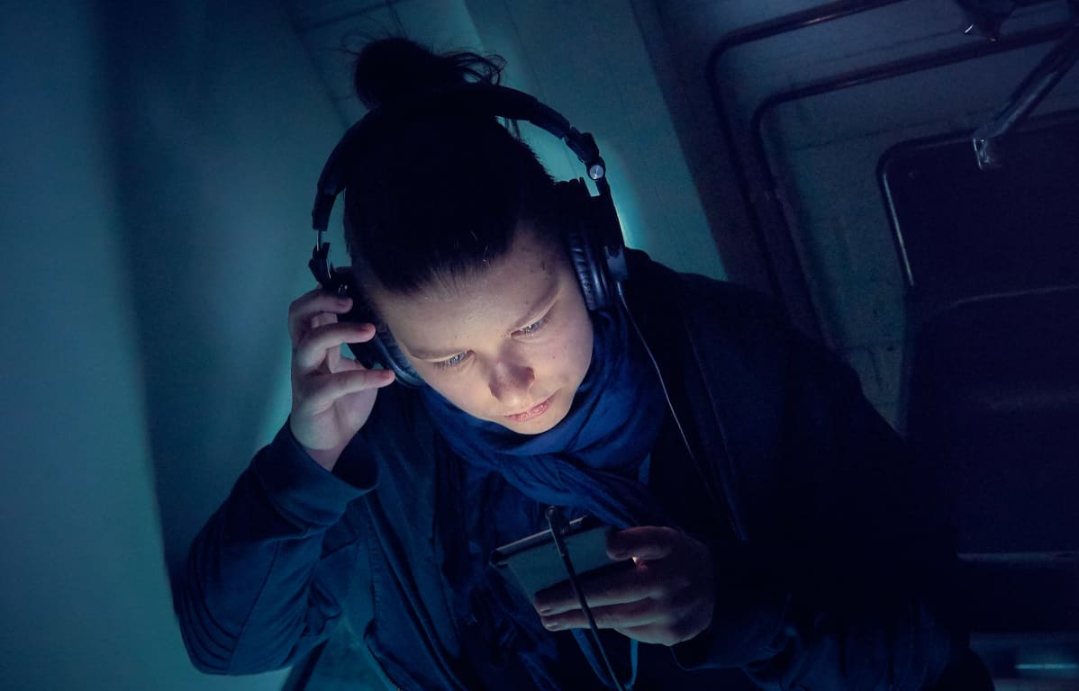 Nuori nainen kuuntelee podcastia matkapuhelimesta