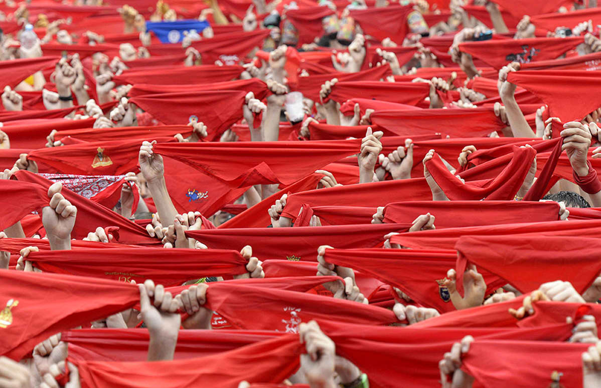 San Fermin -festivaalin osallistujat pitelevät perinteisiä punaisia huiveja festivaalin avajaisissa Pamplonan keskusaukiolla.