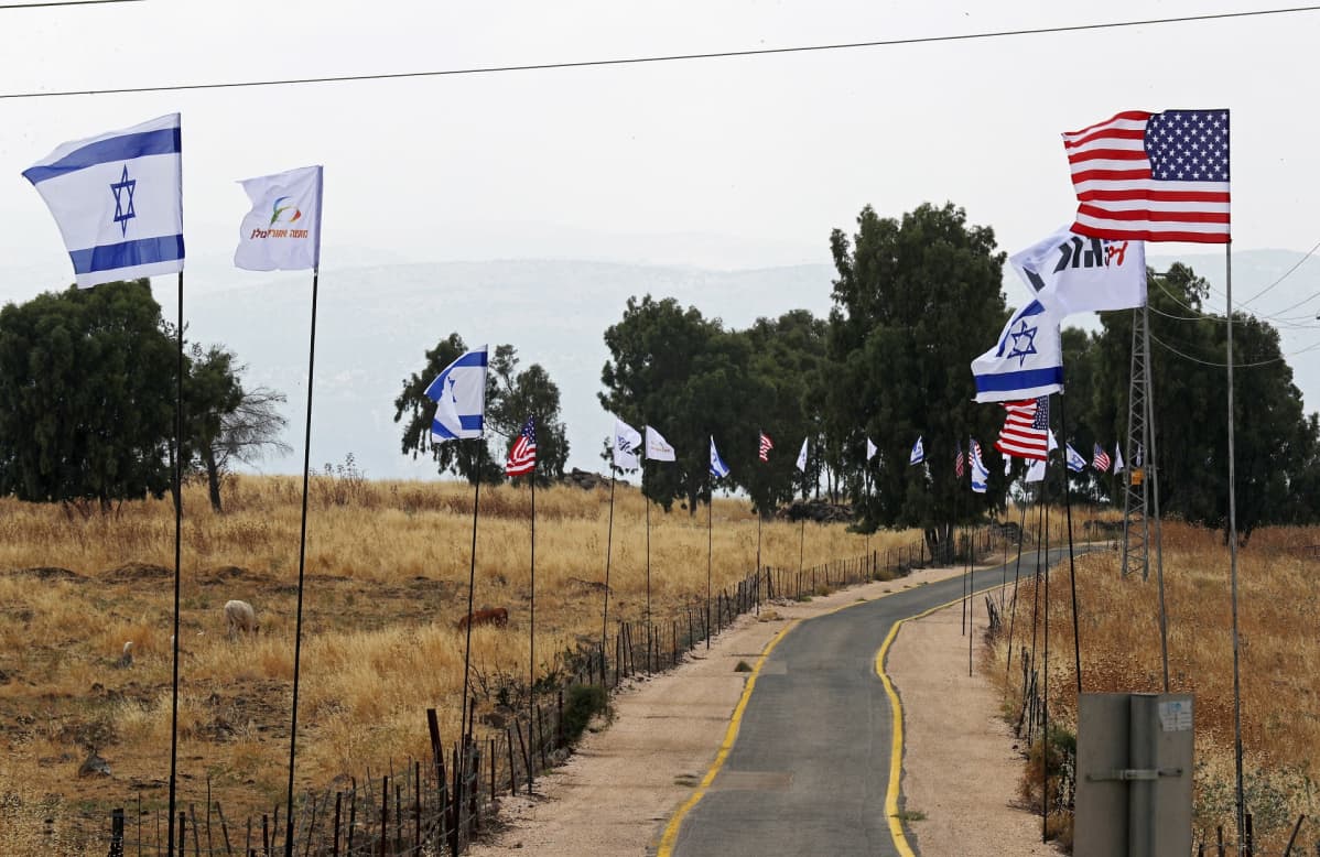 USA:n ja Israelin liput liehuvat tien varsillla.