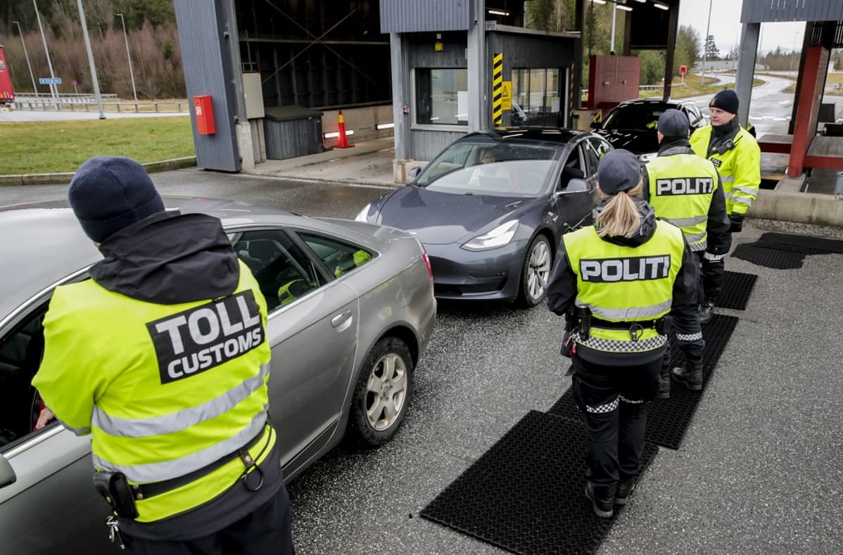 Neljä keltaisiin liiveihin pukeutunutta tulli- ja poliisimiestä tarkistamassa autojonoa.