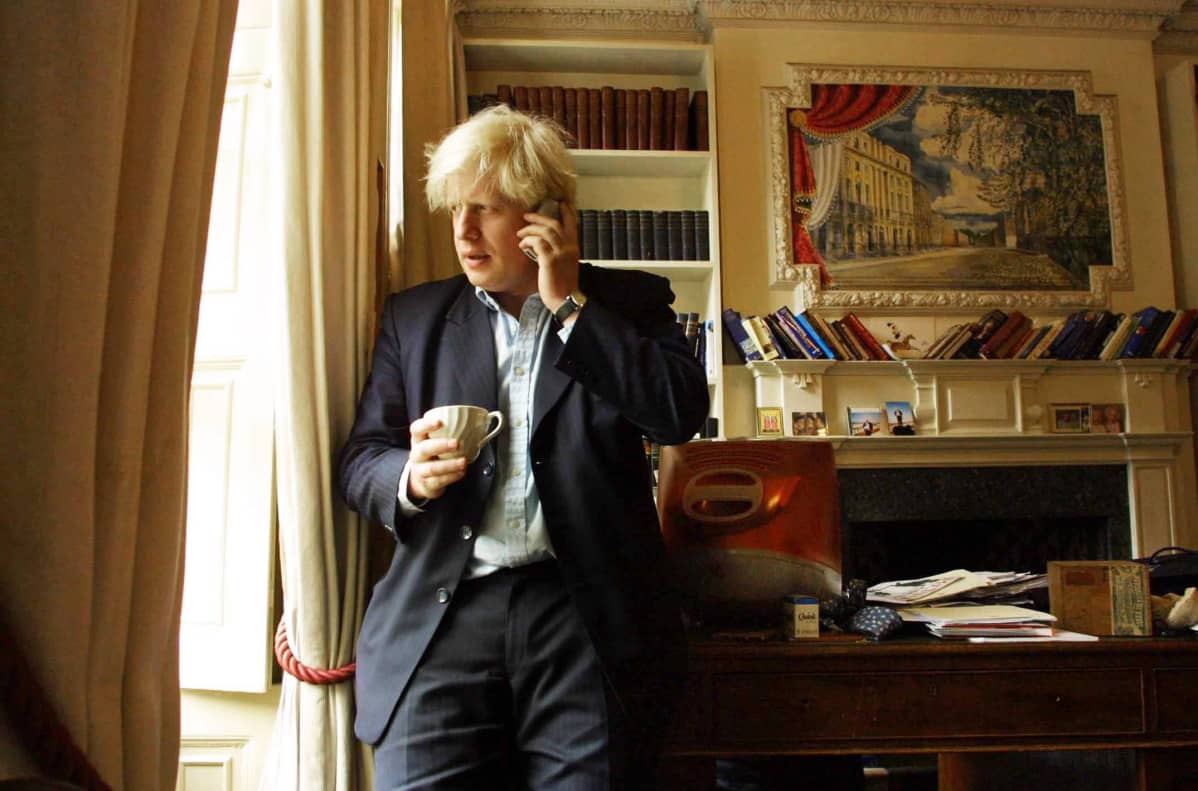 Boris Johnson toimistossa puhuen puhelimeen.