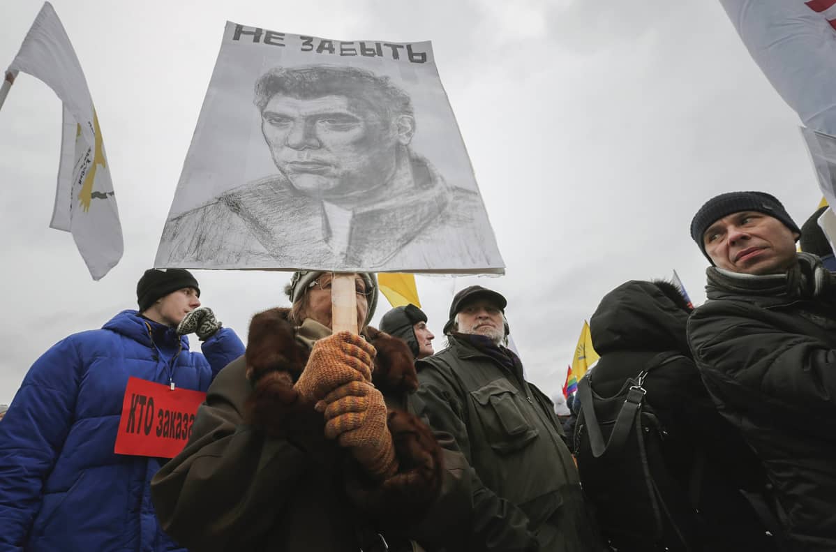 Nainen pitelee kylttiä johon piirretty Boris Nemtsov kuva.