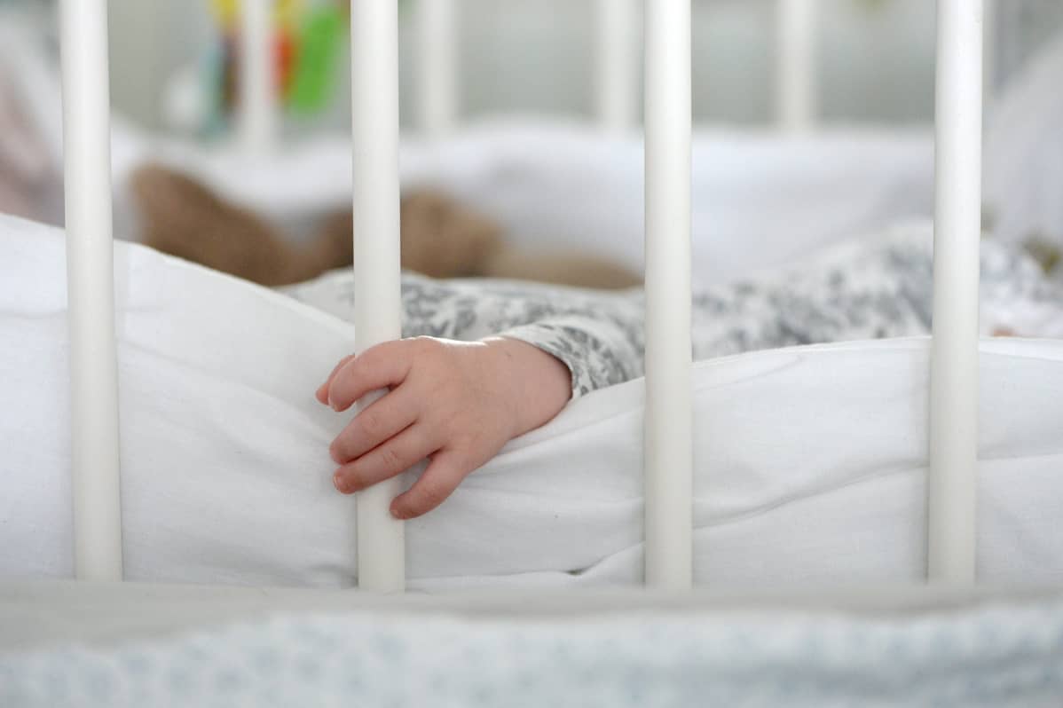 Vauvan käsi puristaa pinnasängyn pinnaa.